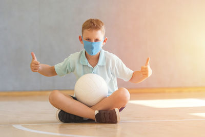 Portrait of boy wearing mask sitting on floor