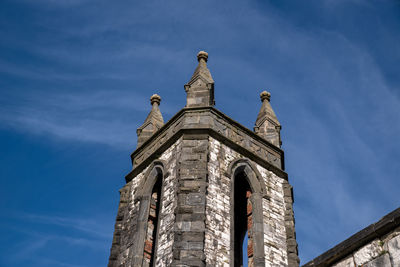 Low angle view of bird perching on building against sky