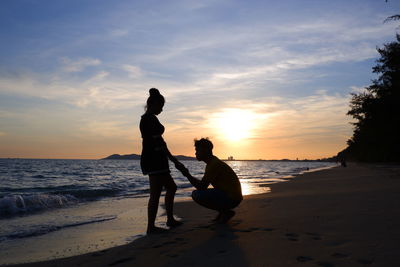 Silhouette people on beach against sky during sunset