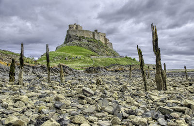 Stone wall by rocks against sky
