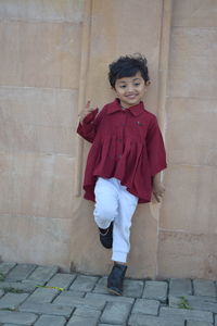 Portrait of smiling girl standing against wall