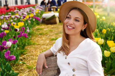 Smiling girl sitting relaxed between tulips fields on springtime. looking to the side.