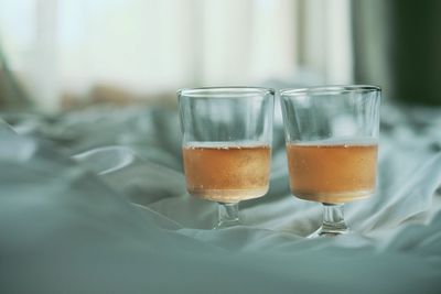 Close-up of wine in wineglasses on bed