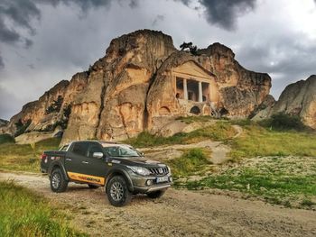 Abandoned car on mountain road against sky