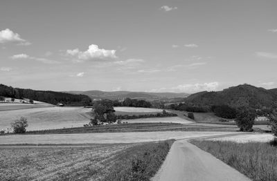 Road amidst field against sky
