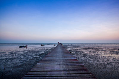 Pier over sea against clear sky at sunset