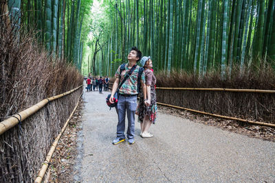 Smiling couple standing on pathway amidst bamboos at arashiyama