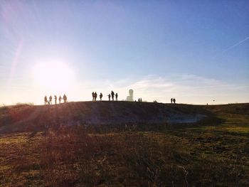 People walking on field against sky