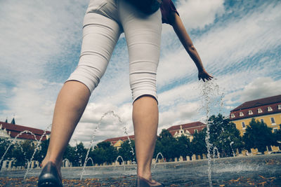 Low section of woman walking in city against sky