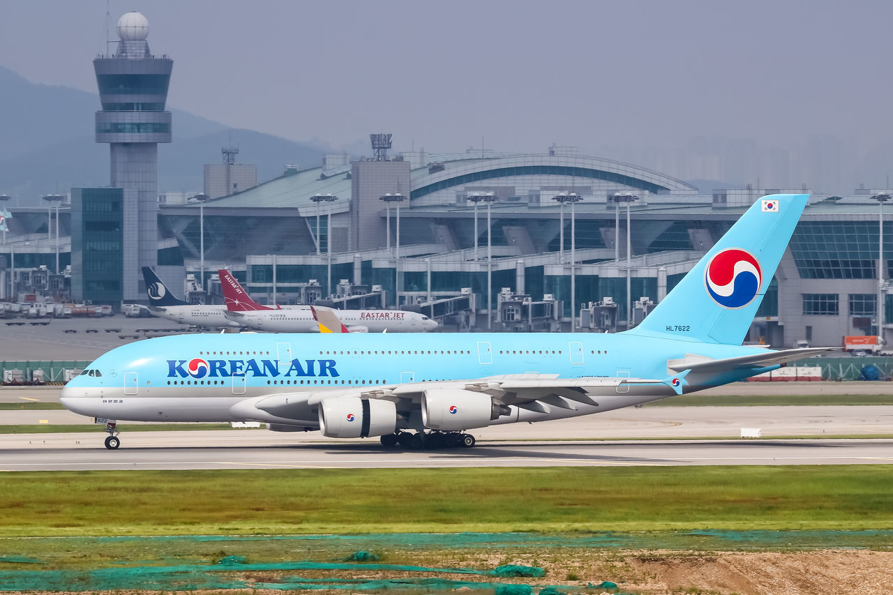 AIRPLANE FLYING OVER AIRPORT AGAINST SKY