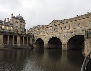 Arch bridge over river against sky