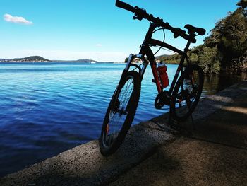 Bicycle by sea against sky