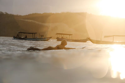 Female surfer in the ocean at sunset