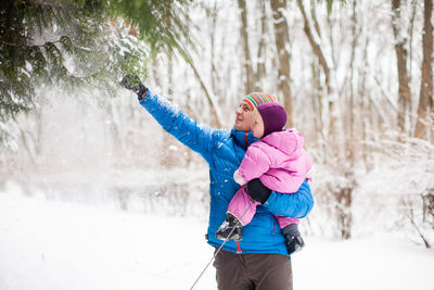 Rear view of woman with arms raised in winter