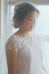 Close-up of woman standing by window at home