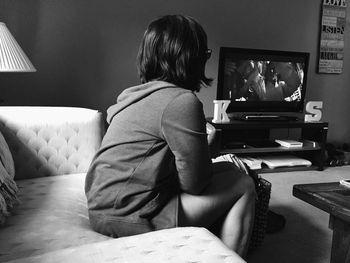 Woman watching television while sitting at home