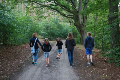 Rear view of woman walking on footpath in forest
