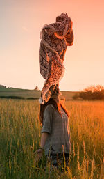 Full length of child standing on field against sky during sunset