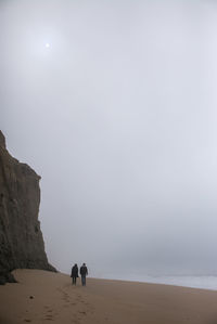 People walking on beach against sky
