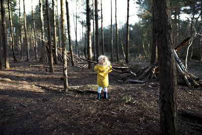 Rear view of playful girl carrying stick in forest