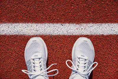 Top view of white male running sneakers near start line at stadium track. fitness and healthy