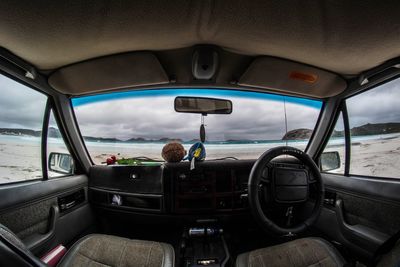 View of car on landscape against cloudy sky