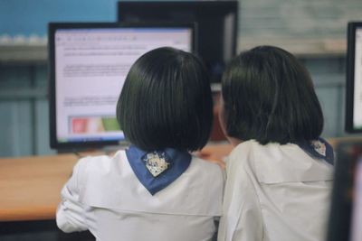 Rear view of two women in laptop