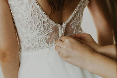 The girl fastens the bride's dress.