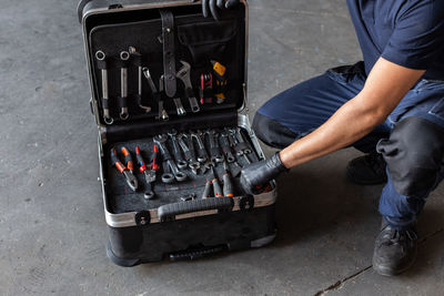 From above unrecognizable male technician picking screwdriver bits from tool box while working in garage