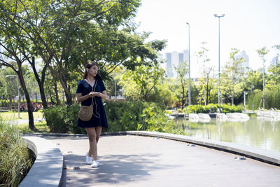 Full length of woman listening music while walking at park