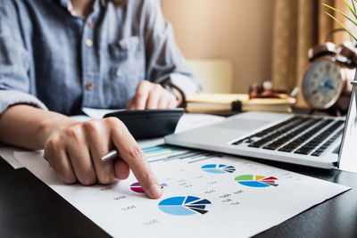 Midsection of man using laptop on table