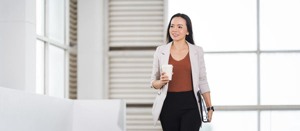 Young woman standing against wall