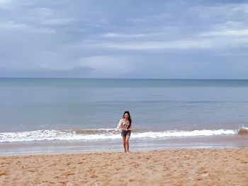 Full length of man standing on beach against sky