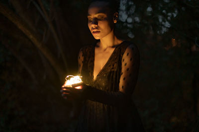 Young woman standing against illuminated fire in the dark
