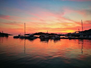Boats moored at harbor during sunset