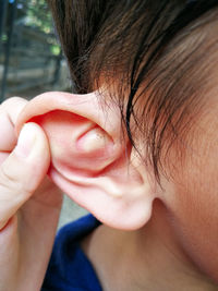 Close-up of hand holding person ear