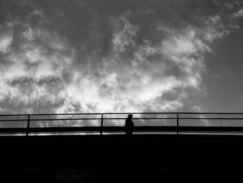 Silhouette man standing on bridge against sky