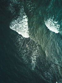 High angle aerial view of two surfers in the sea.