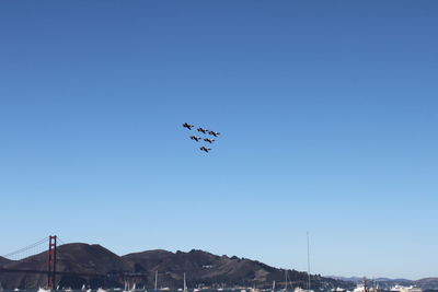 Low angle view of airplane flying against clear blue sky