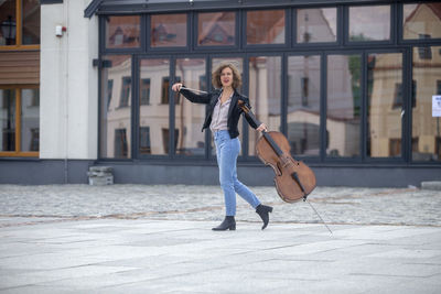 Full length of woman with violin on street