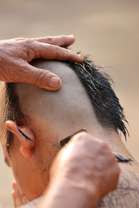 Cropped image of monk cutting hair of man during ordination