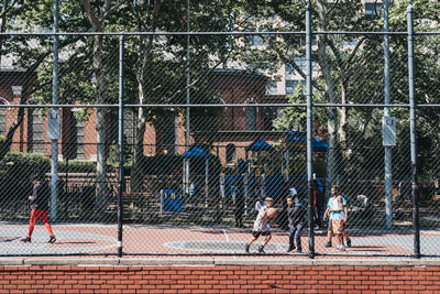 Group of people playing field seen through chainlink fence
