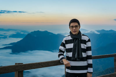 Portrait of young man standing against mountains