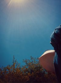 Man holding umbrella against clear blue sky