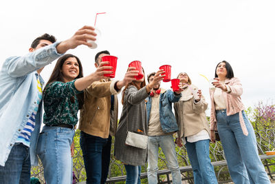 Group of friends standing against clear sky