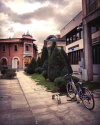 Bicycles parked on street by buildings against sky