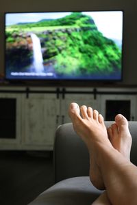 Low section of woman relaxing on sofa at home