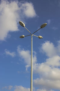 Low angle view of street light against cloudy blue sky on sunny day