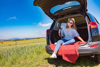 Full length of woman sitting on field against sky