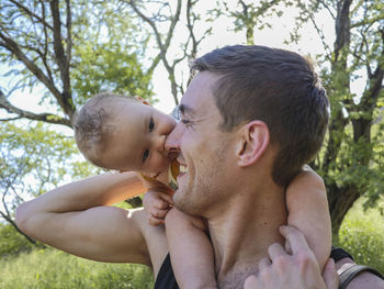 Close-up of father carrying cute daughter on shoulders in forest